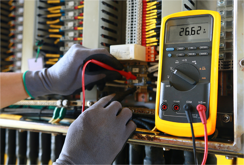 Electrician using multimeter on circuit board.